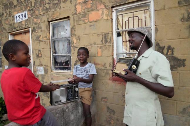 Ngwiza Khumbulani Moyo, a vintage collector, shows a young boy some of his old radio sets outside his home in Bulawayo.