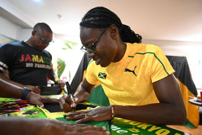 
Roneisha McGregor signs a Jamaican flag during a visit to the Jamaican Embassy in Tokyo.