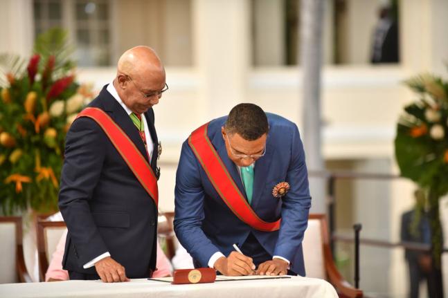Governor General Sir Patrick Allen (left) watches as Prime Minister Dr Andrew Holness signs the Instrument of Appointment during his Swearing-In Ceremony at King’s House in St Andrew on Tuesday.