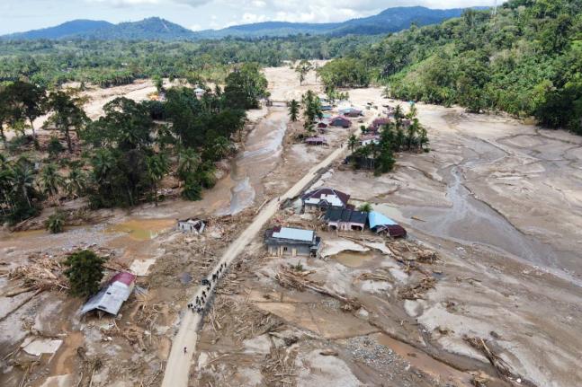 People walk along a road in a village affected by a flash flood in Batang Toru, North Sumatra, Indonesia on December 1, 2025. 