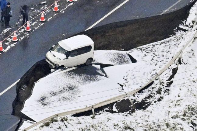 This aerial photo shows a vehicle sitting on a damaged road in Tohoku town, Aomori prefecture, northern Japan Tuesday, December 9, 2025, following a powerful earthquake on late Monday. (Kyodo News via AP)
