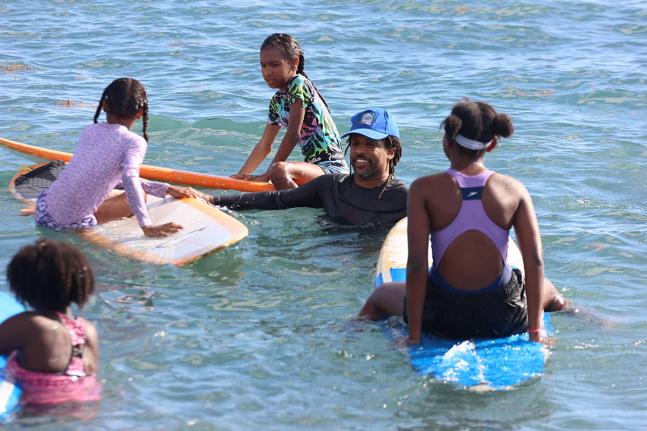 President of the Jamaica Surfing Association, Inilek Wilmot (second right), interacts with some of the children at the Next Wave JA surfing session in Bull Bay on Sunday. 