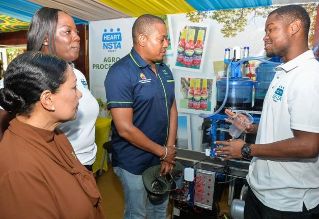 Instructor of Mechatronics and Mobile Robotics at HEART/NSTA Trust, Derrick Rochester Campus, Dihanroy Mitchell (right), explains the use of Mechatronics in Agro-Food and Beverage Processing to Minister of Agriculture, Fisheries and Mining, Floyd Green (th